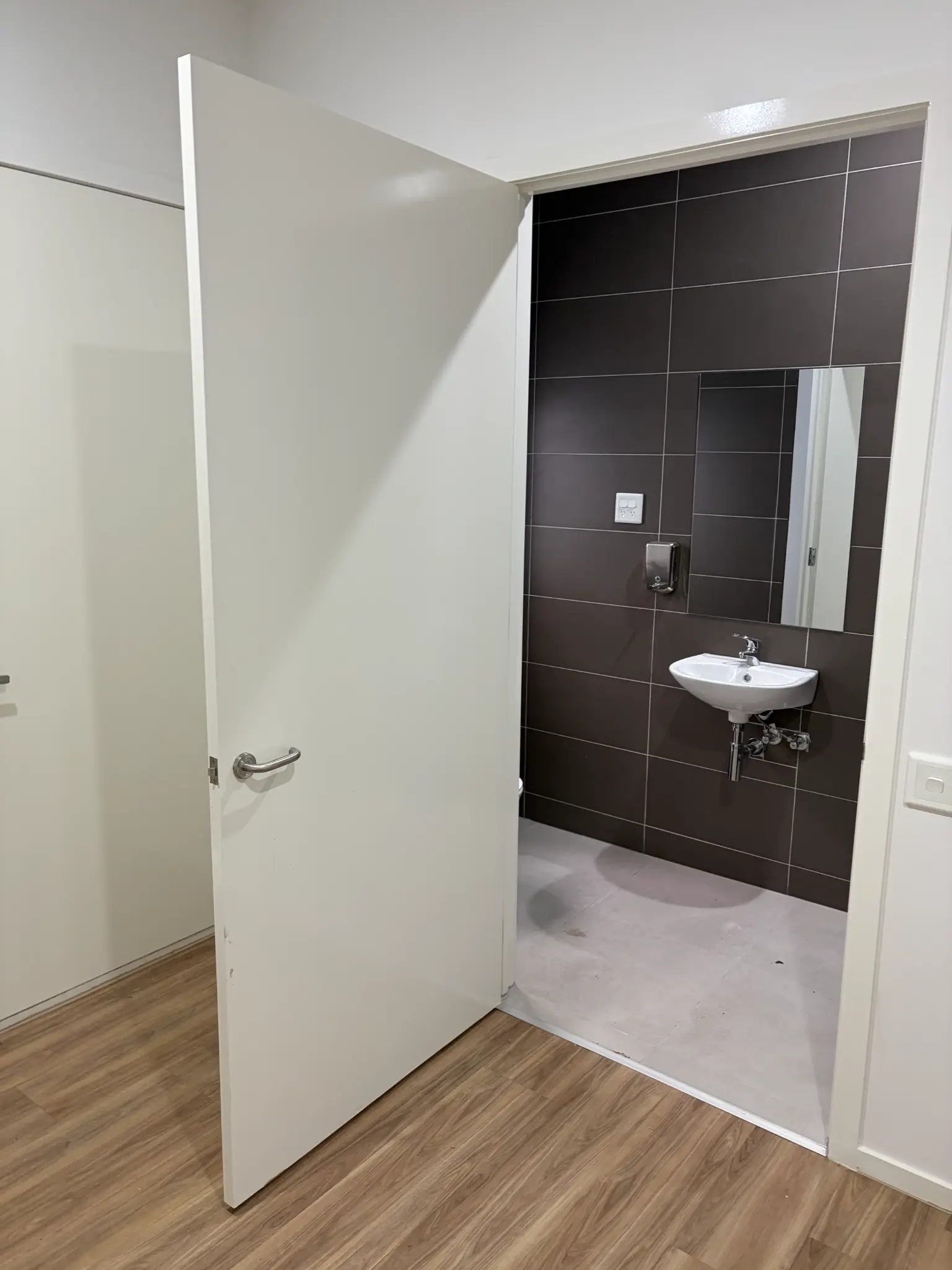 Completed bathroom renovation with dark tiled walls and a white basin